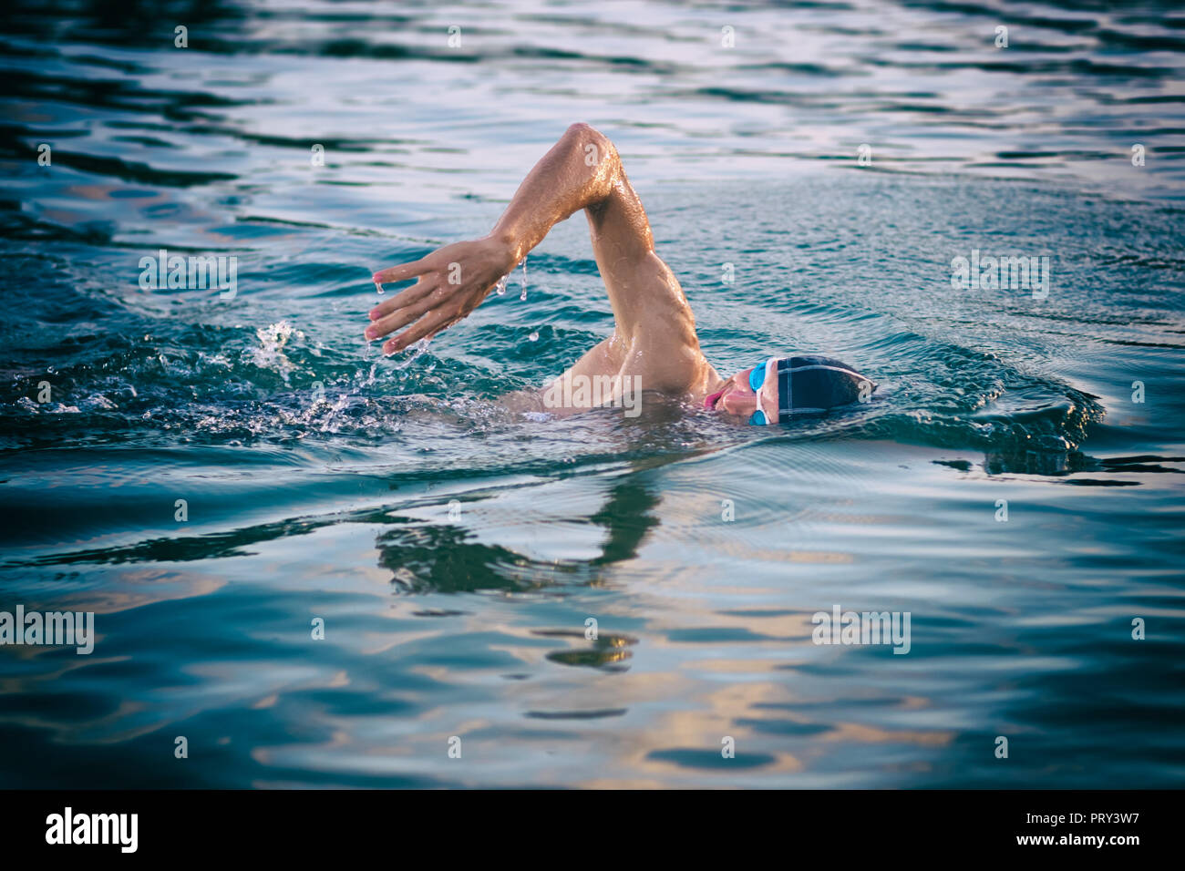 Nuotatore respirazione durante il nuoto crawl in mare al tramonto Foto Stock