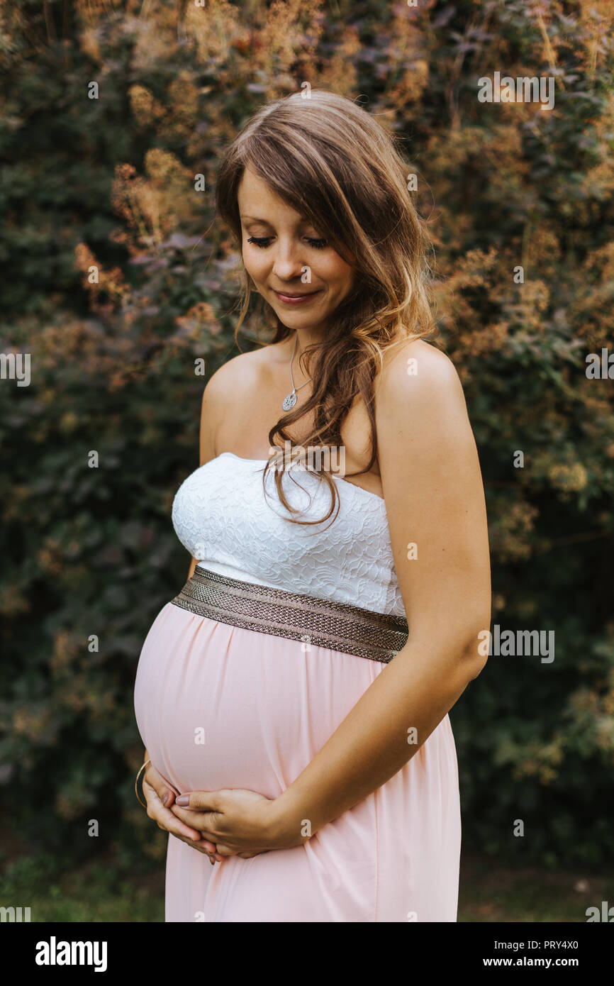 Ritratto di donna incinta mentre tiene il suo ventre Foto Stock