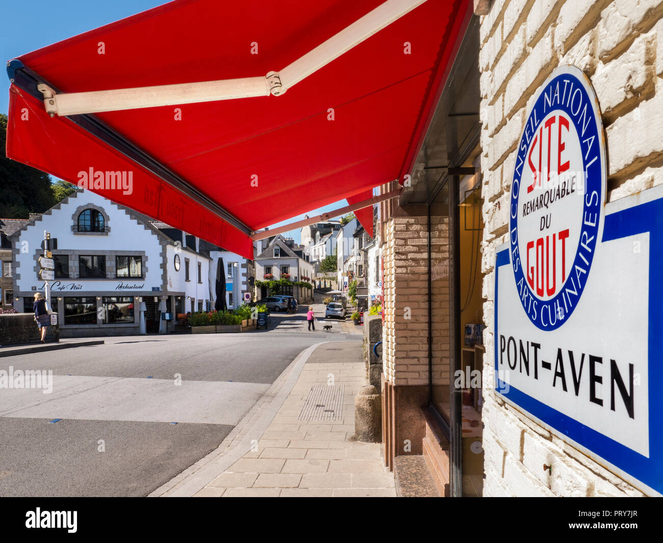 Ponte di Pont-Aven con negozio culinaria e la placca "mirabile luogo per sapore e gusto' con tenda rossa e tranquilla atmosfera da villaggio Pont-Aven Brittany Foto Stock