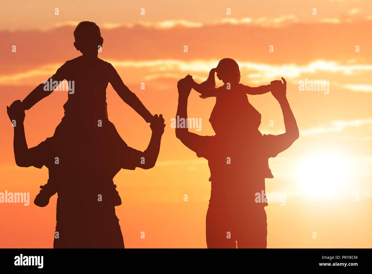 Silhouette di nonni che trasportano i loro nipoti sulla spalla al tramonto Foto Stock