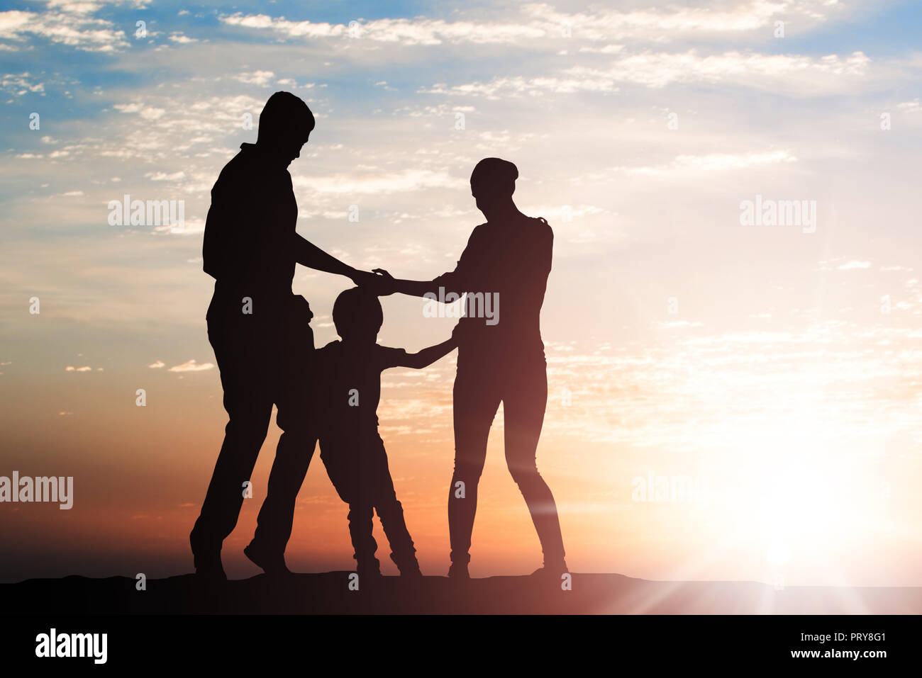 Silhouette di famiglia in esecuzione nel cerchio tenendo le mani al tramonto Foto Stock