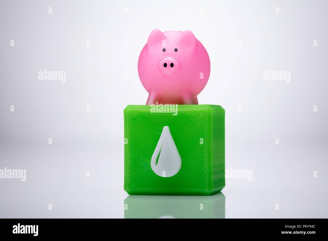 Close-up di un rosa Piggybank su Blocco cubico con Waterdrop icona sullo sfondo riflettente Foto Stock