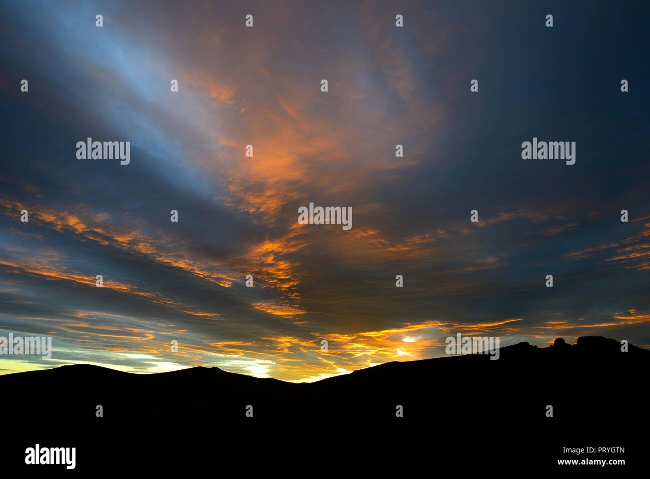 Tramonto spettacolare con crescente nuvole temporalesche nella parte anteriore del silhouette di montagna, Pali Aike National Park, Magallanes Provincia del Cile Foto Stock