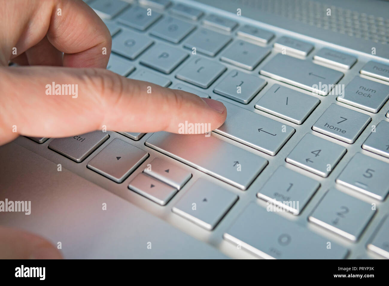 Close-up di digitazione mani maschio. grigio silver pulsante tastiera vicino, dito preme il pulsante INVIO. La lingua inglese e la luce rossa tastiera per hack Foto Stock