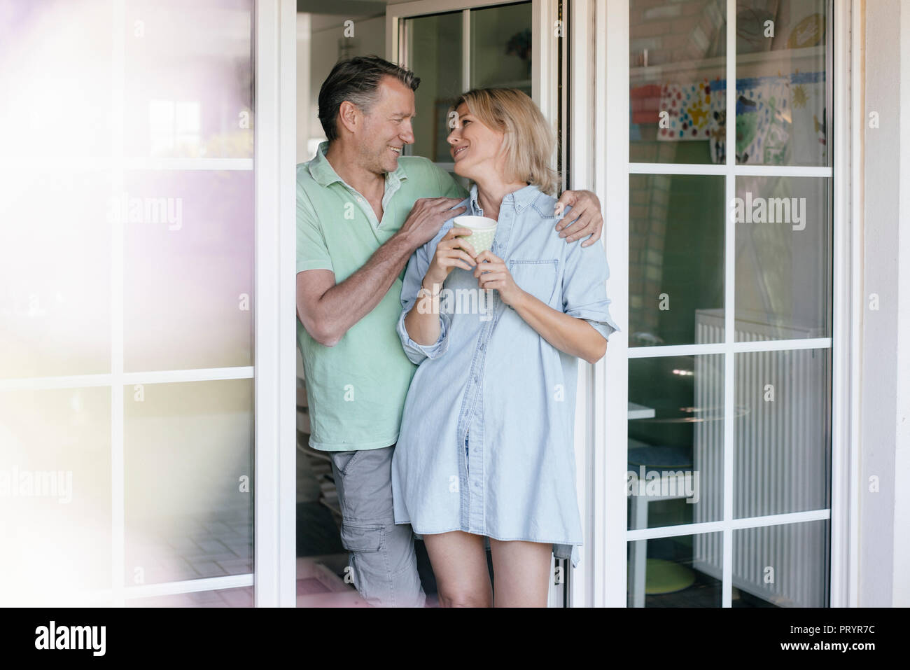Felice Coppia matura in piedi alla finestra francese Foto Stock