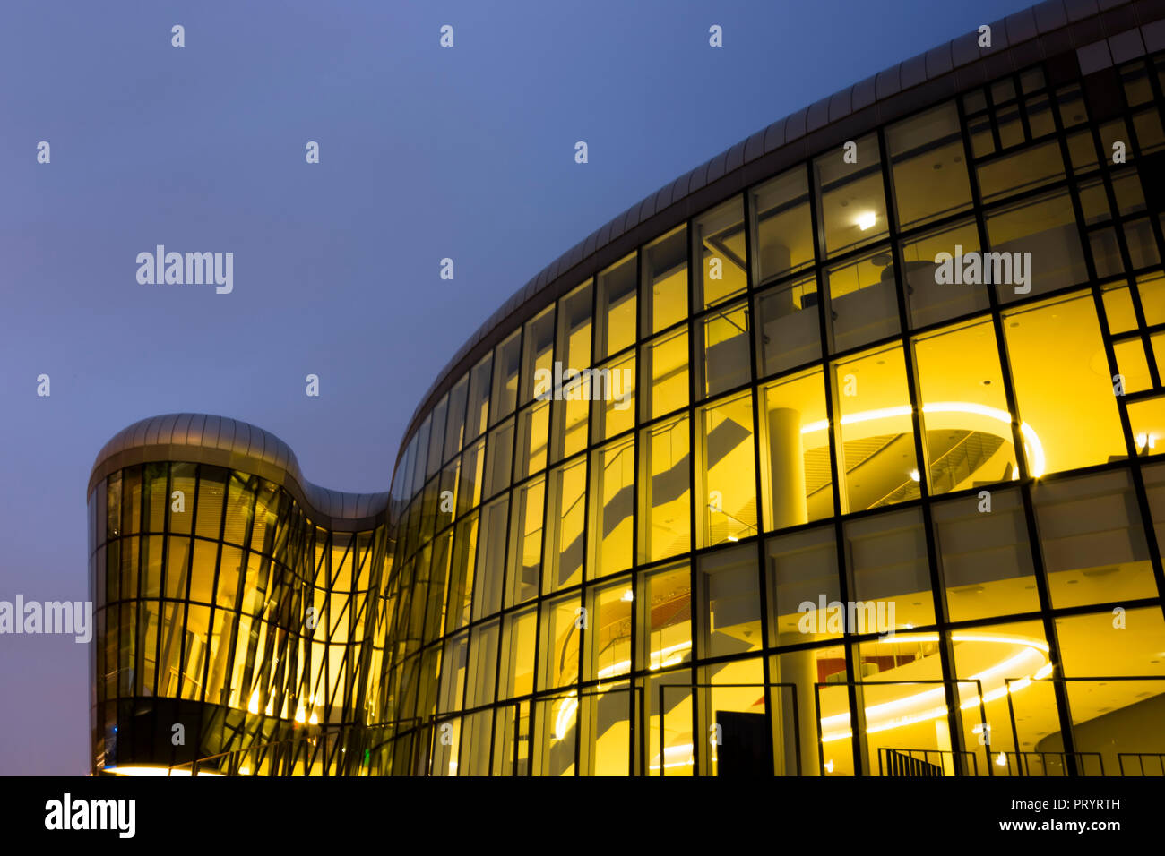 La Polonia, Cracovia, facciata in vetro illuminate del centro congressi presso il blue ora Foto Stock
