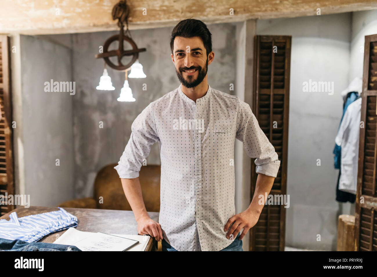 Ritratto di uomo sorridente indossando camicia nel negozio di abbigliamento uomo Foto Stock