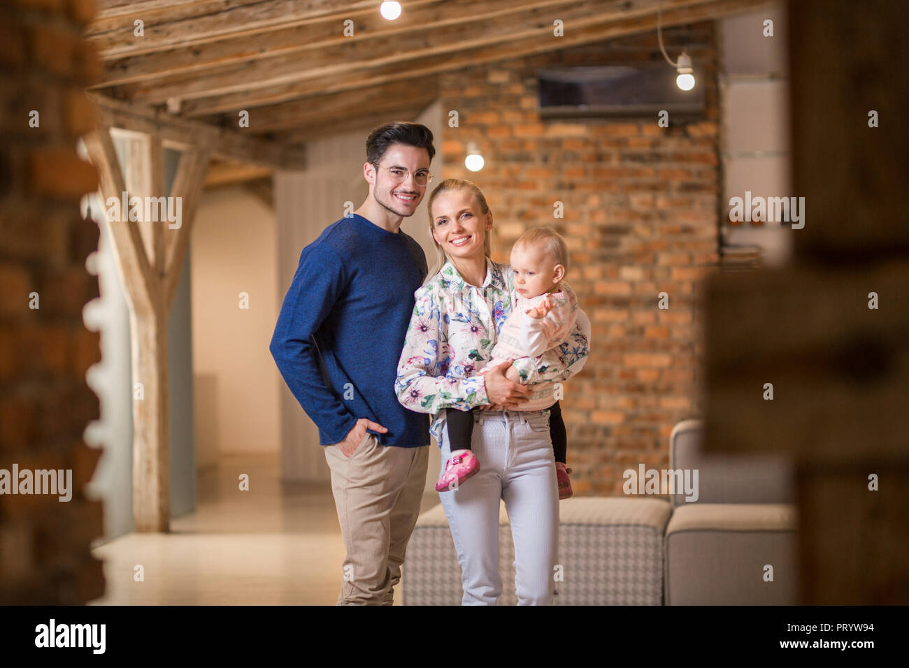 Ritratto di felice giovani genitori con la loro bambina a casa Foto Stock