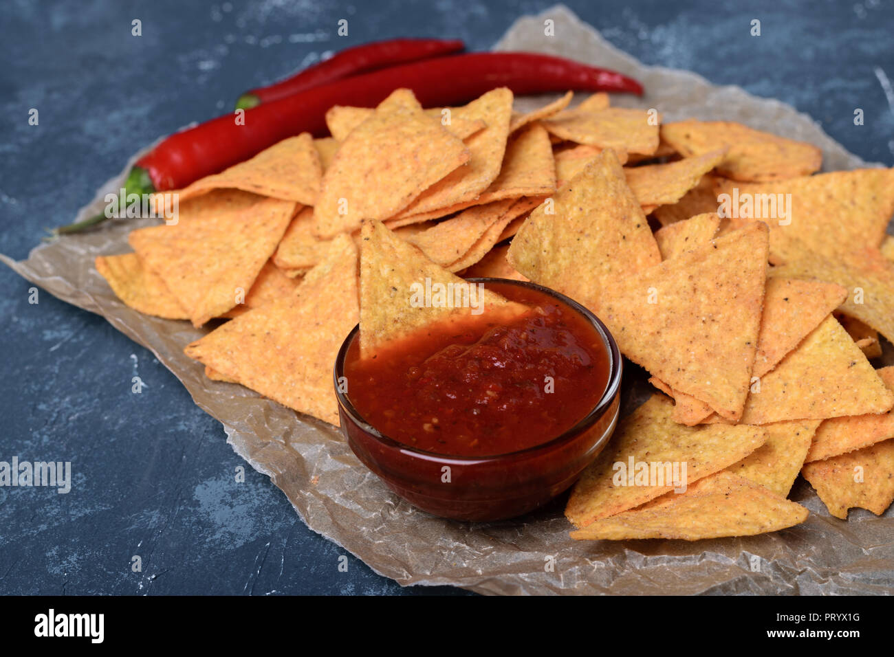 Messicano gustosa tortilla chips con salsa di pomodoro in salsa di blu scuro dello sfondo in calcestruzzo. Foto Stock