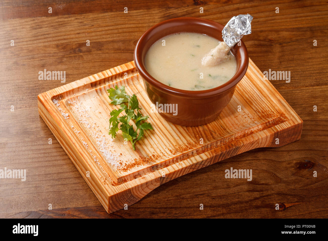 Pollo cremosa zuppa di cosce di pollo disossate servita in una pentola di creta sulla parte superiore di un pannello di legno Foto Stock