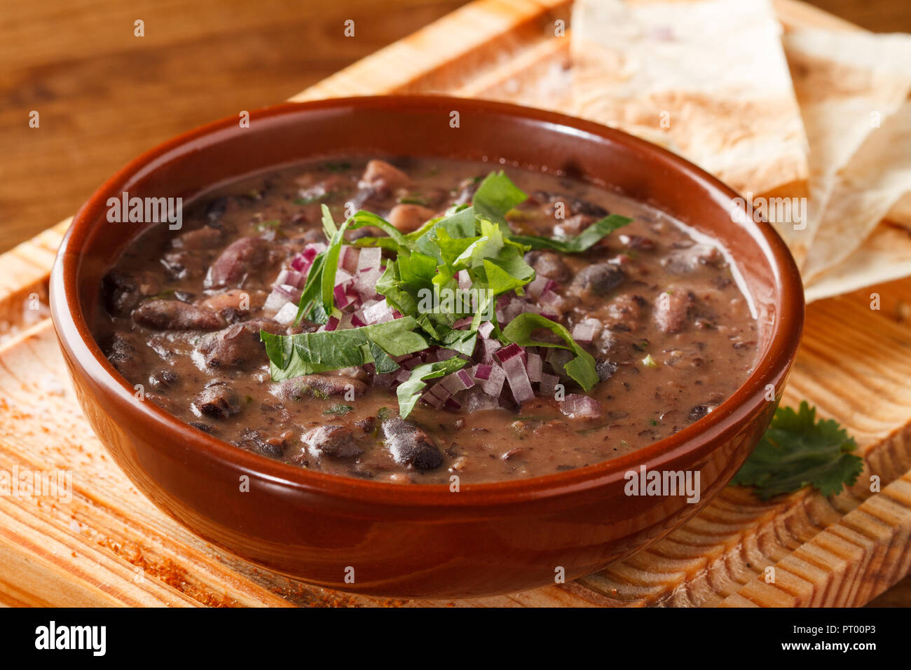 Zuppa di fagioli rossi, servita su un asse di legno con pezzi di pane. Foto Stock