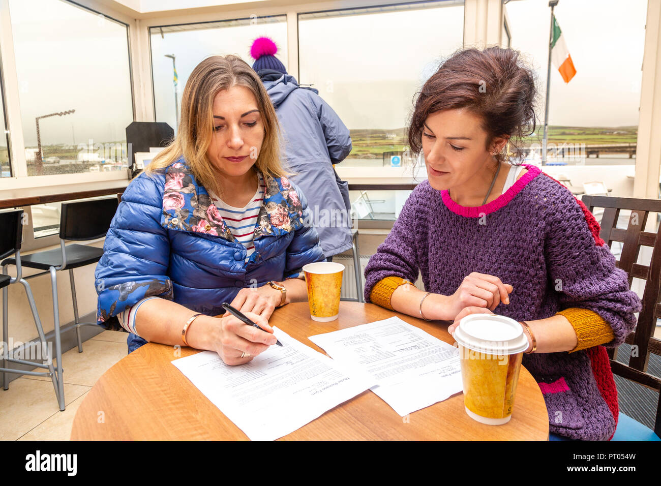 Due donne la firma dei moduli in un cafe, Irlanda Foto Stock