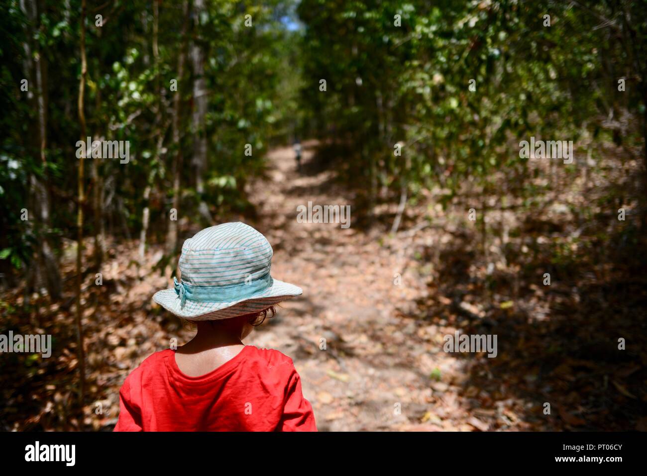 Un giovane bambino rosso da indossare a piedi attraverso una foresta, Dalrymple gap, QLD, Australia Foto Stock