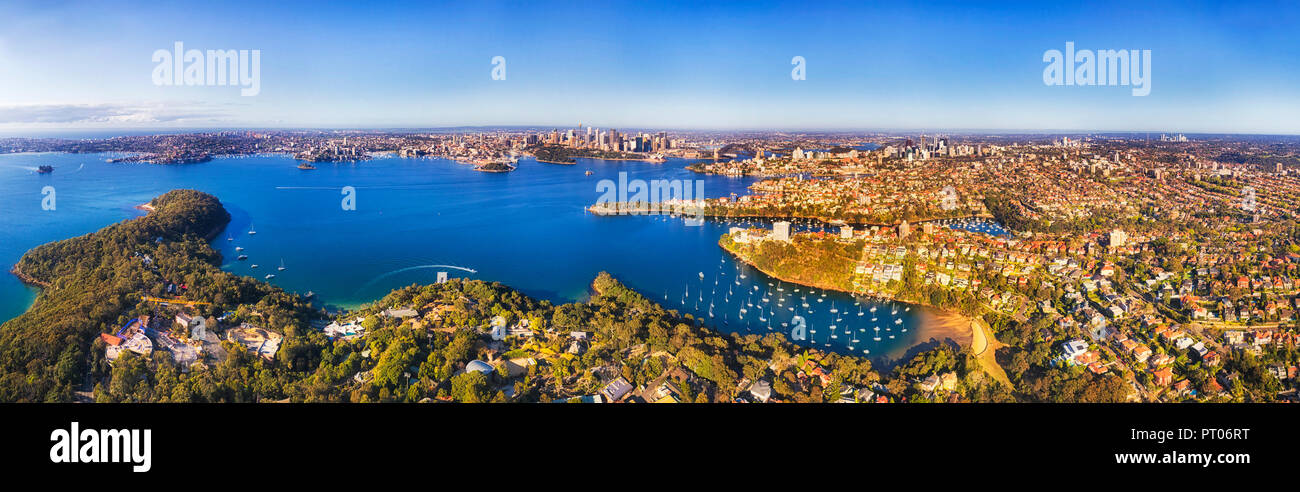 Limpide acque blu del porto di Sydney tra rive sulla luminosa giornata di sole in vista aerea del CBD di Città i punti di riferimento da ricchi della North Shore inferiore nei sobborghi di Foto Stock