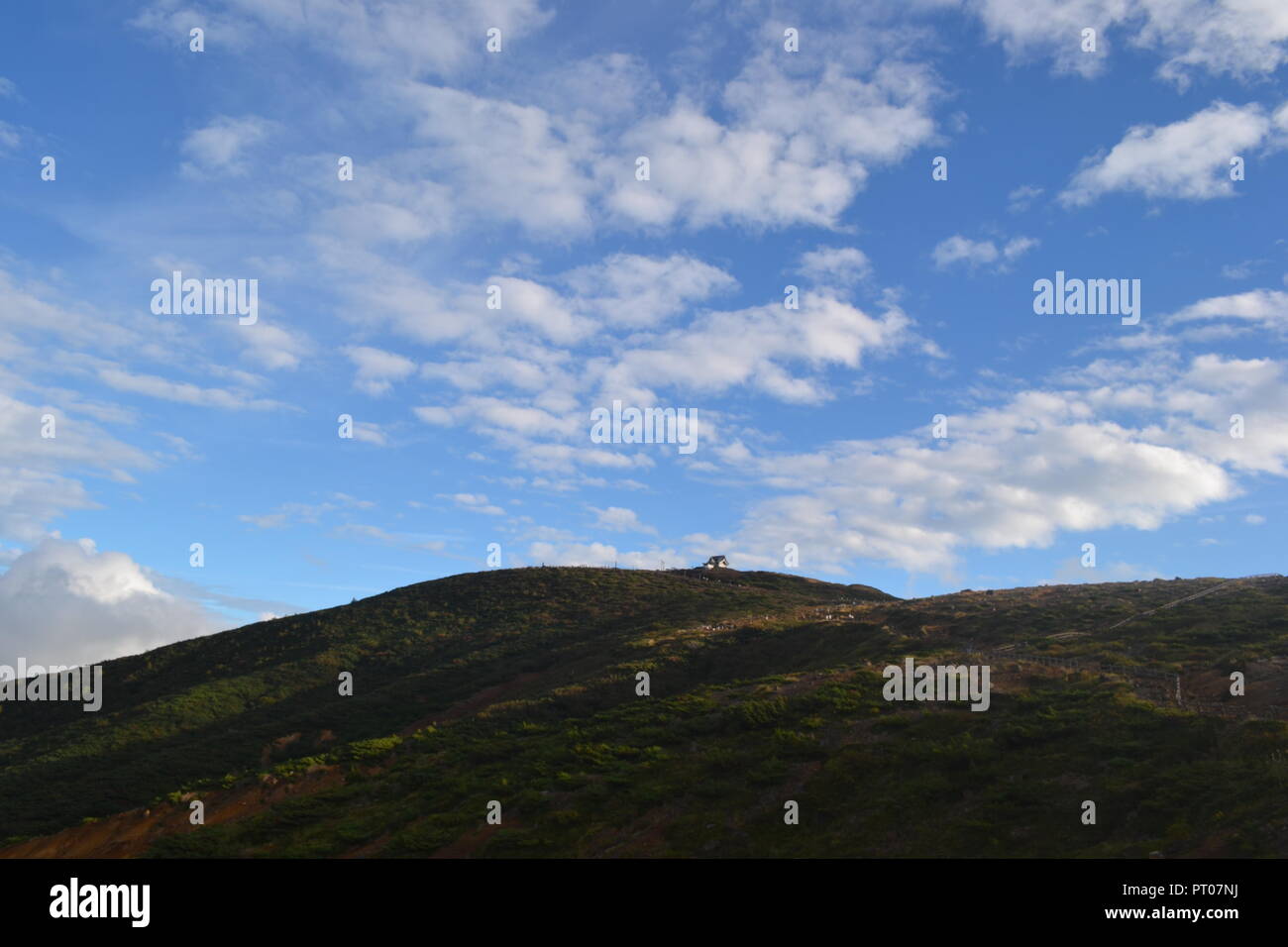 Una collina ed un cielo blu con nuvole Foto Stock