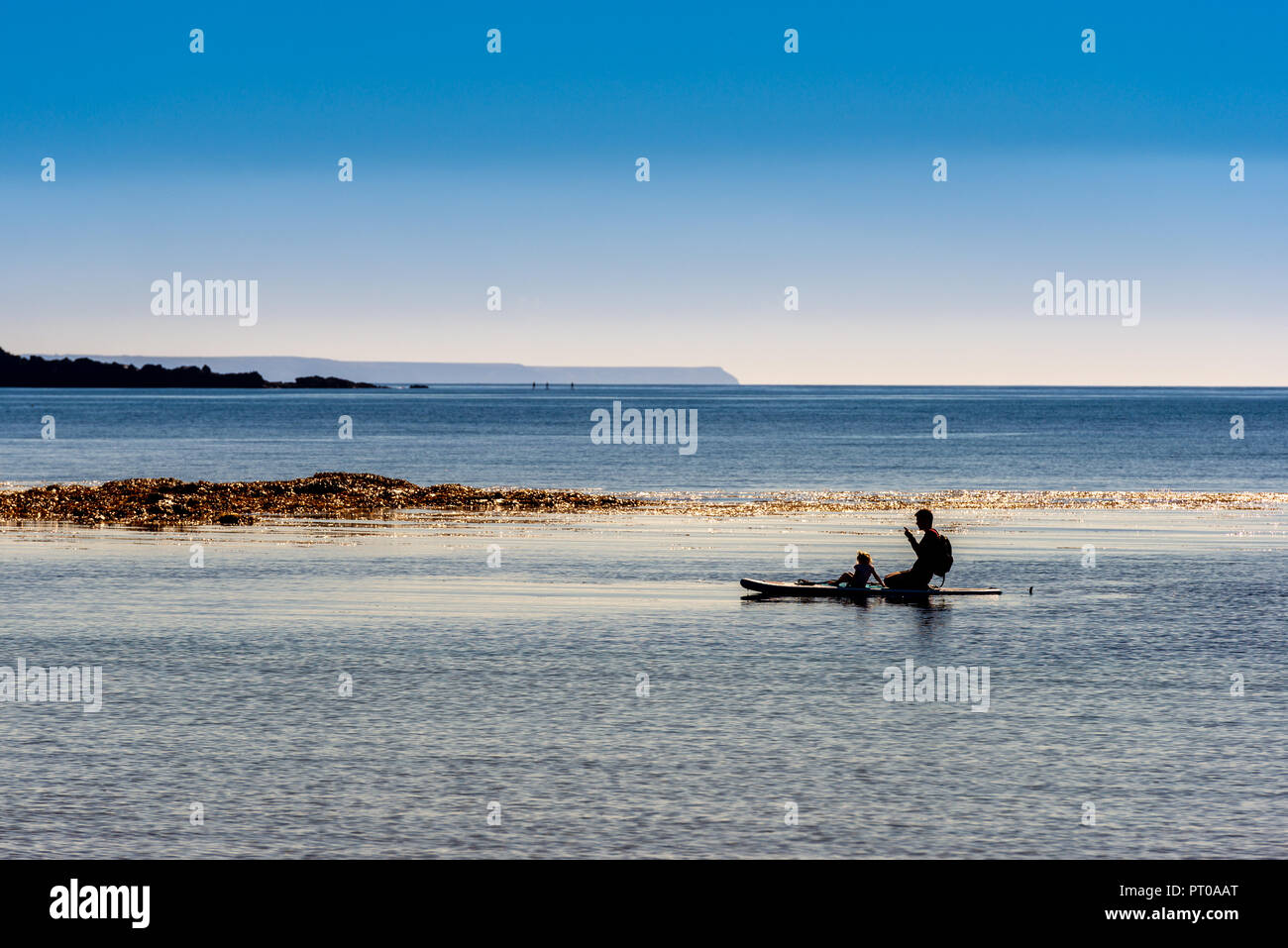 Stagliano paddle-boarder su un mare calmo con cielo chiaro Foto Stock
