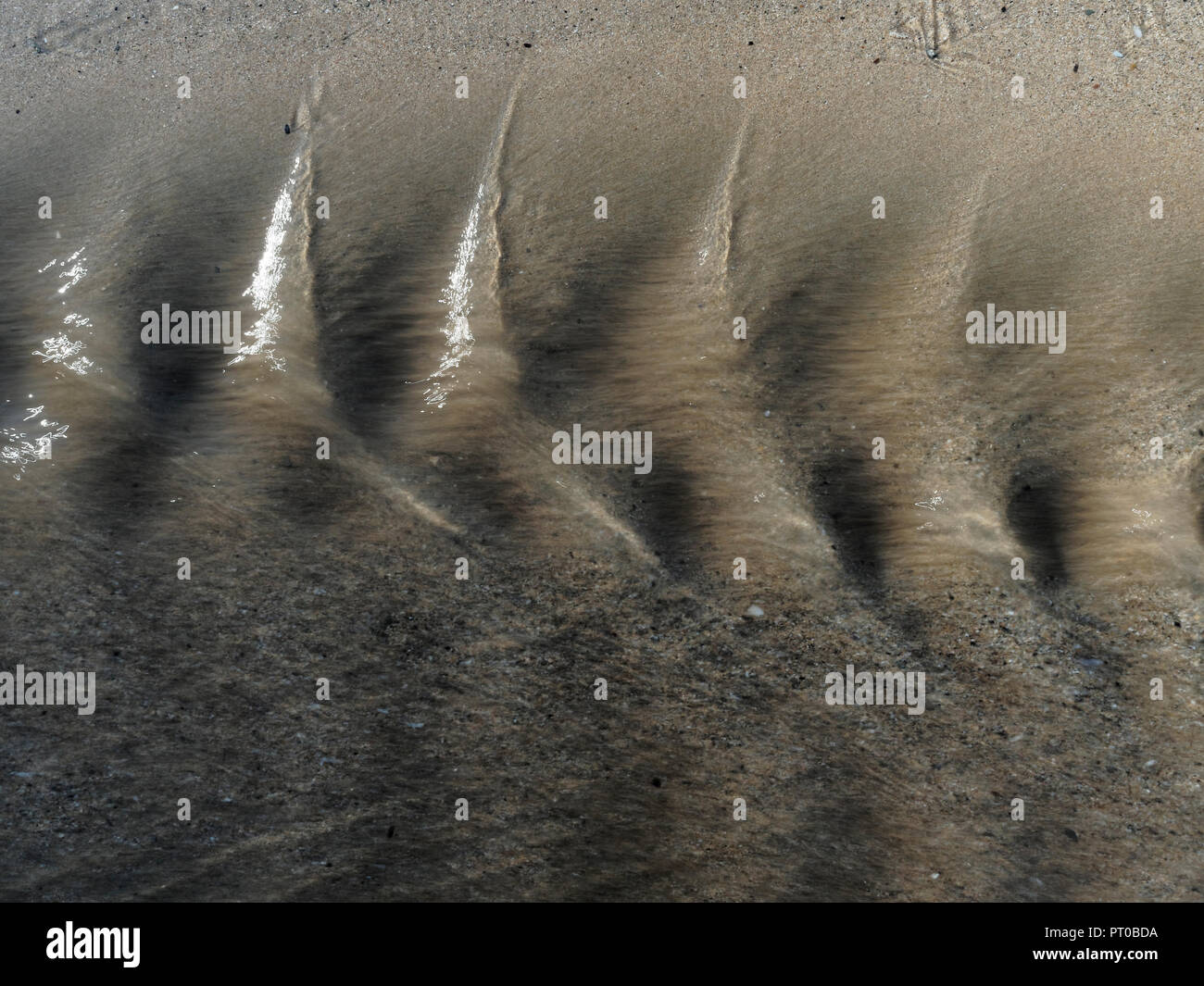 Close up di acqua increspature sulla spiaggia di sabbia Foto Stock