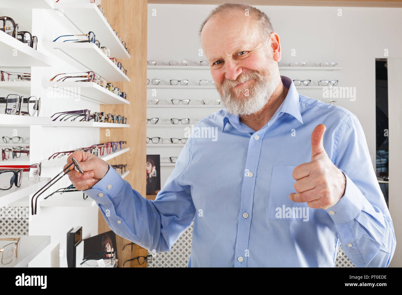 Allegro uomo anziano scelta di occhiali correttivi in ottica store Foto Stock