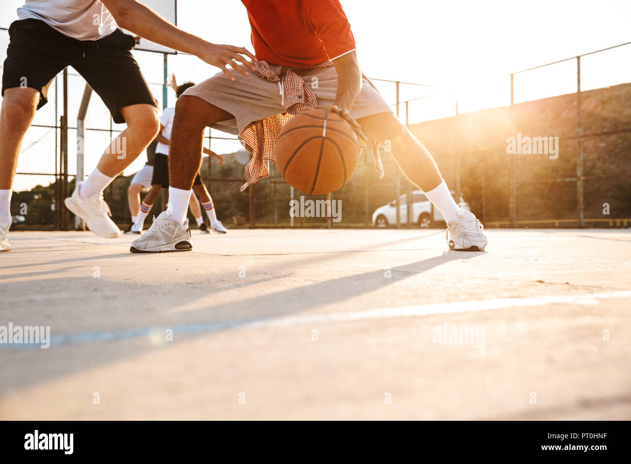 Immagine ritagliata di forti uomini multietnica i giocatori di basket giocare a basket al campo sportivo Foto Stock