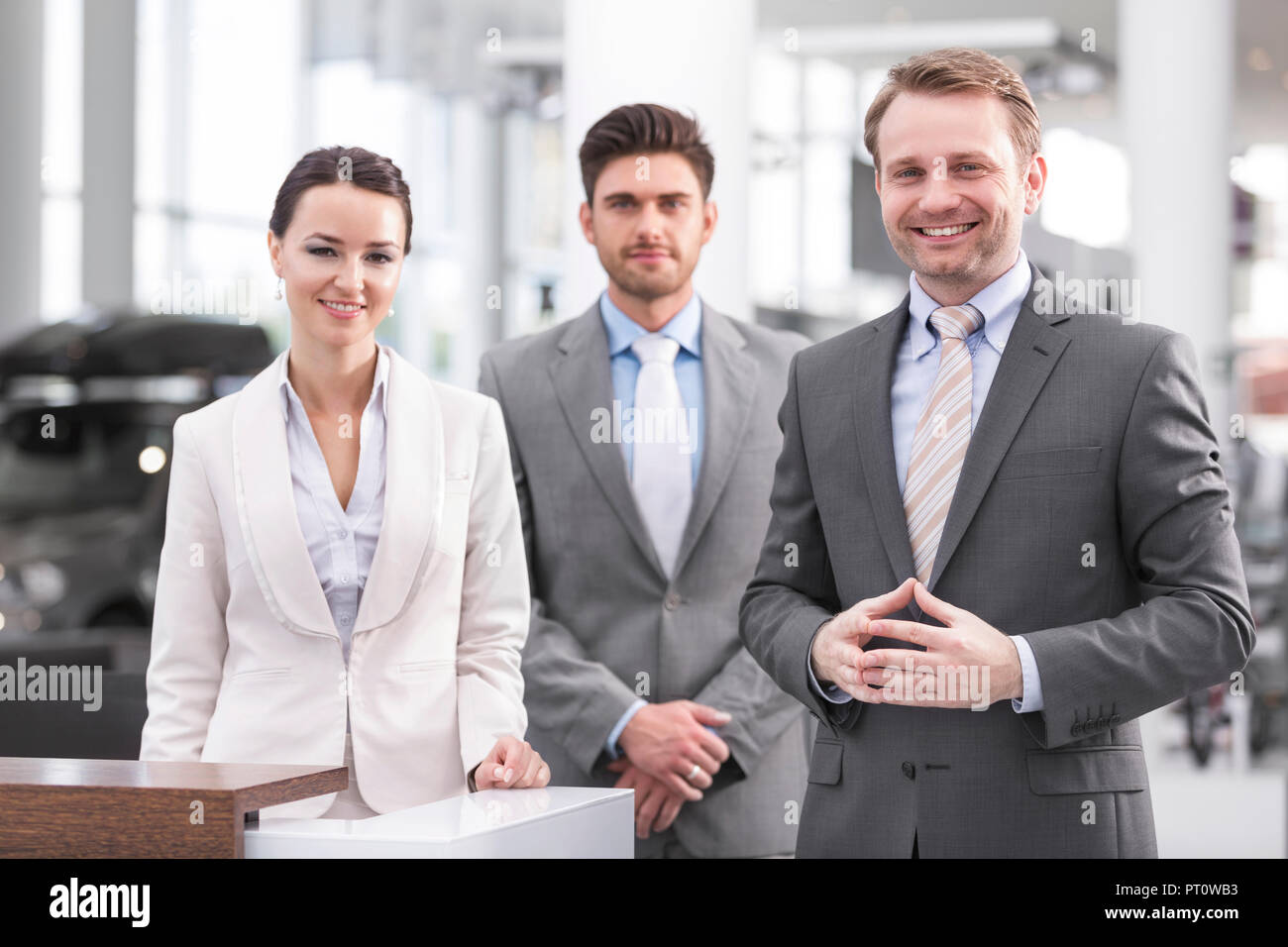 Presso il rivenditore di auto, sorridente la gente di vendite Foto Stock