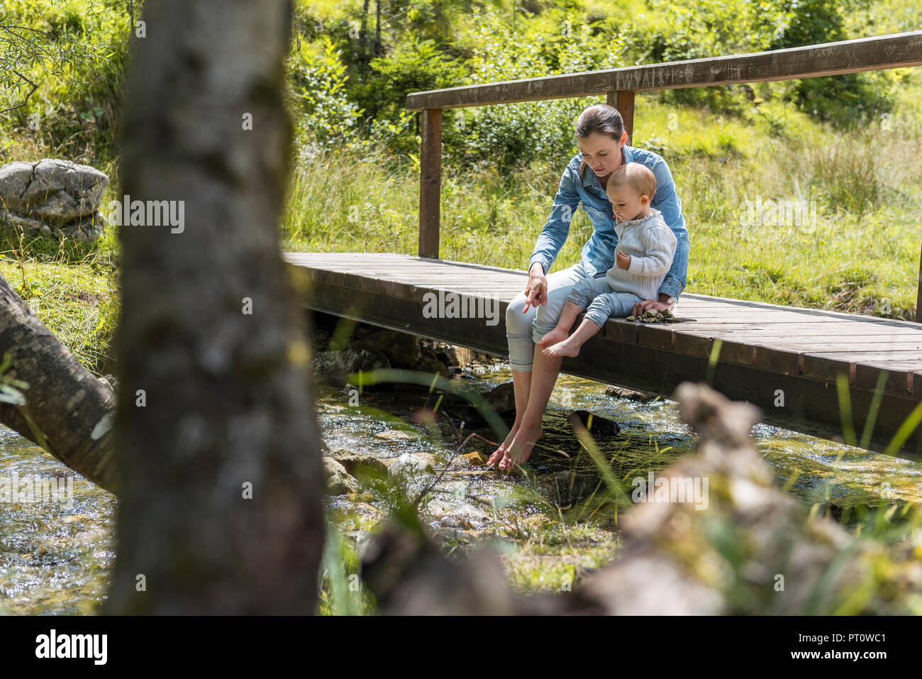 Madre e figlia seduti sul ponte di legno, Ruscello di montagna Foto Stock