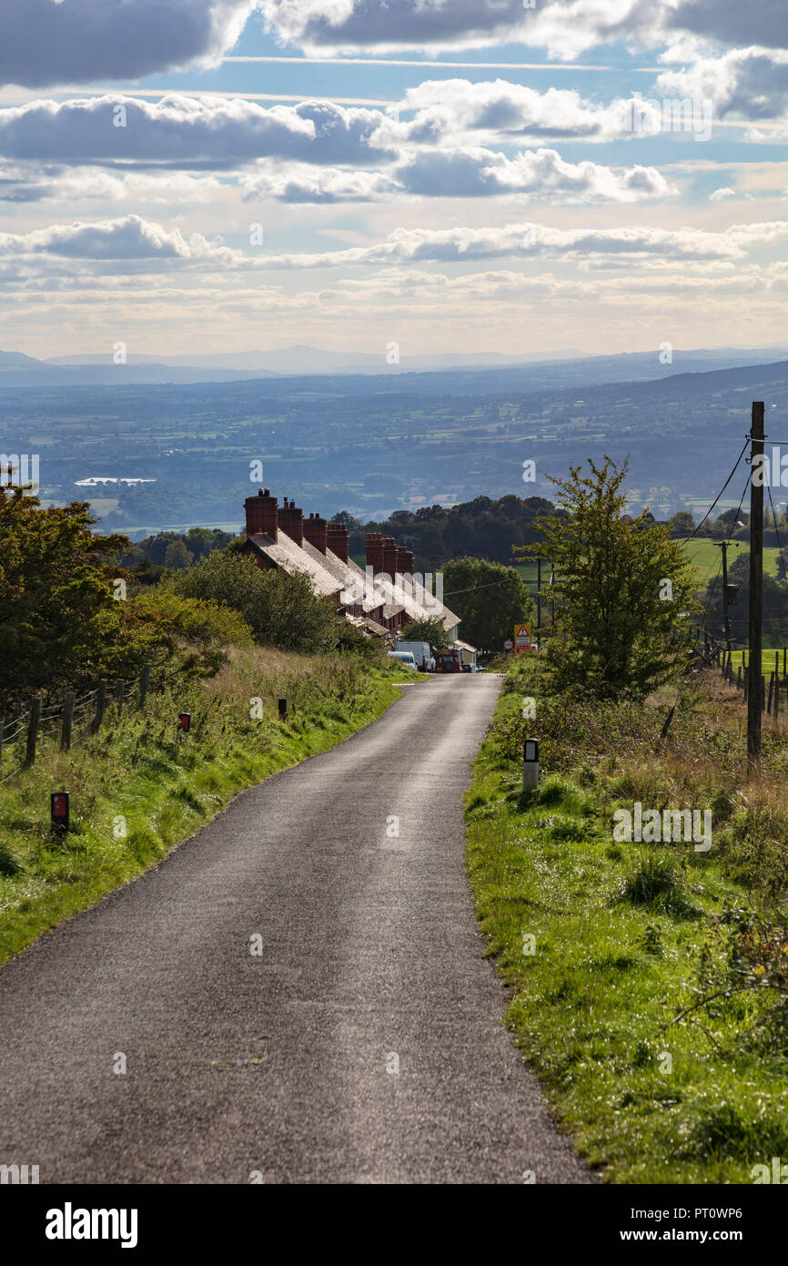 Un avvolgimento lane scende Titterstone Clee Hill verso Ludlow, passato una fila di lavoratori di cava cottages, Shropshire, Regno Unito Foto Stock