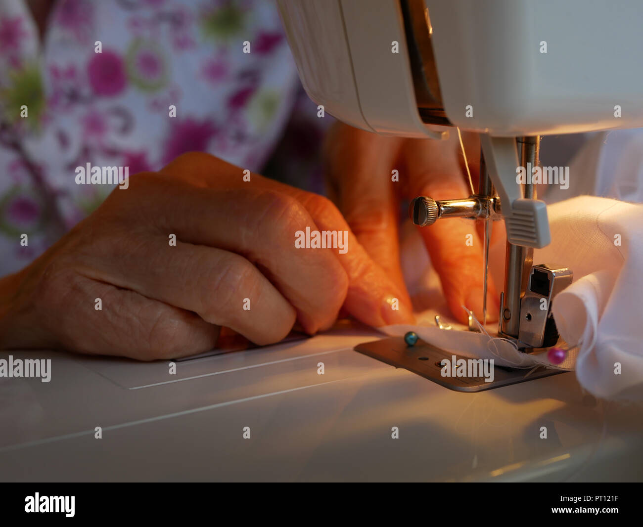 Dettaglio delle mani di una vecchia donna che lavorano su un abito bianco con una macchina da cucire Foto Stock