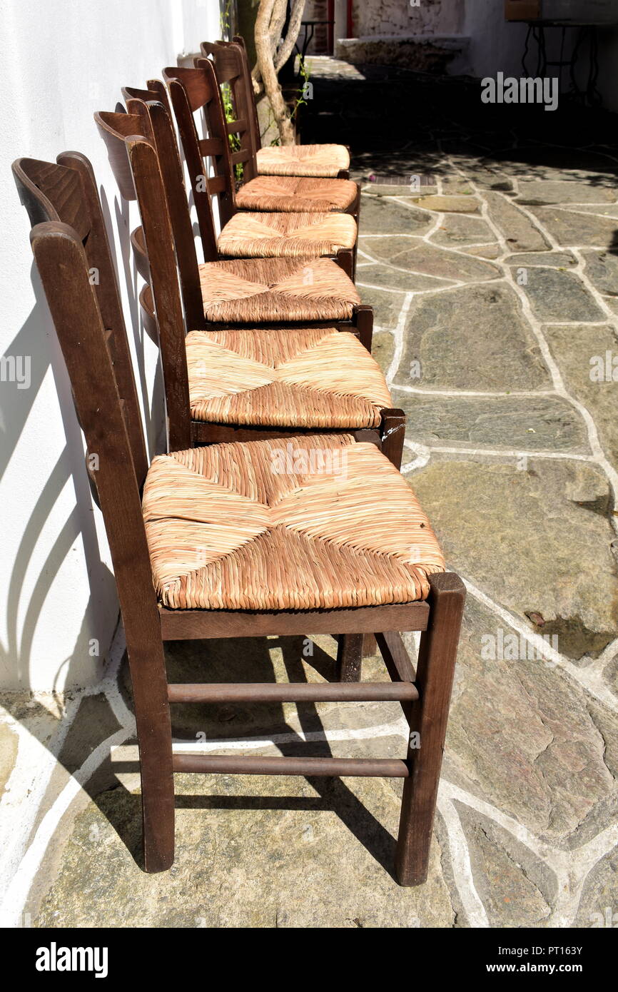 Tradizionali sedie taverna in legno in una fila, in un vicolo presso la  splendida isola greca di Sikinos. Design semplice ed efficace di mobili  Foto stock - Alamy