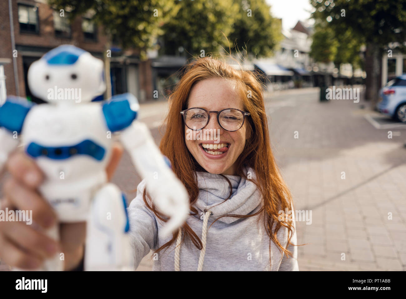 Redheaded donna che mostra il robot giocattolo Foto Stock