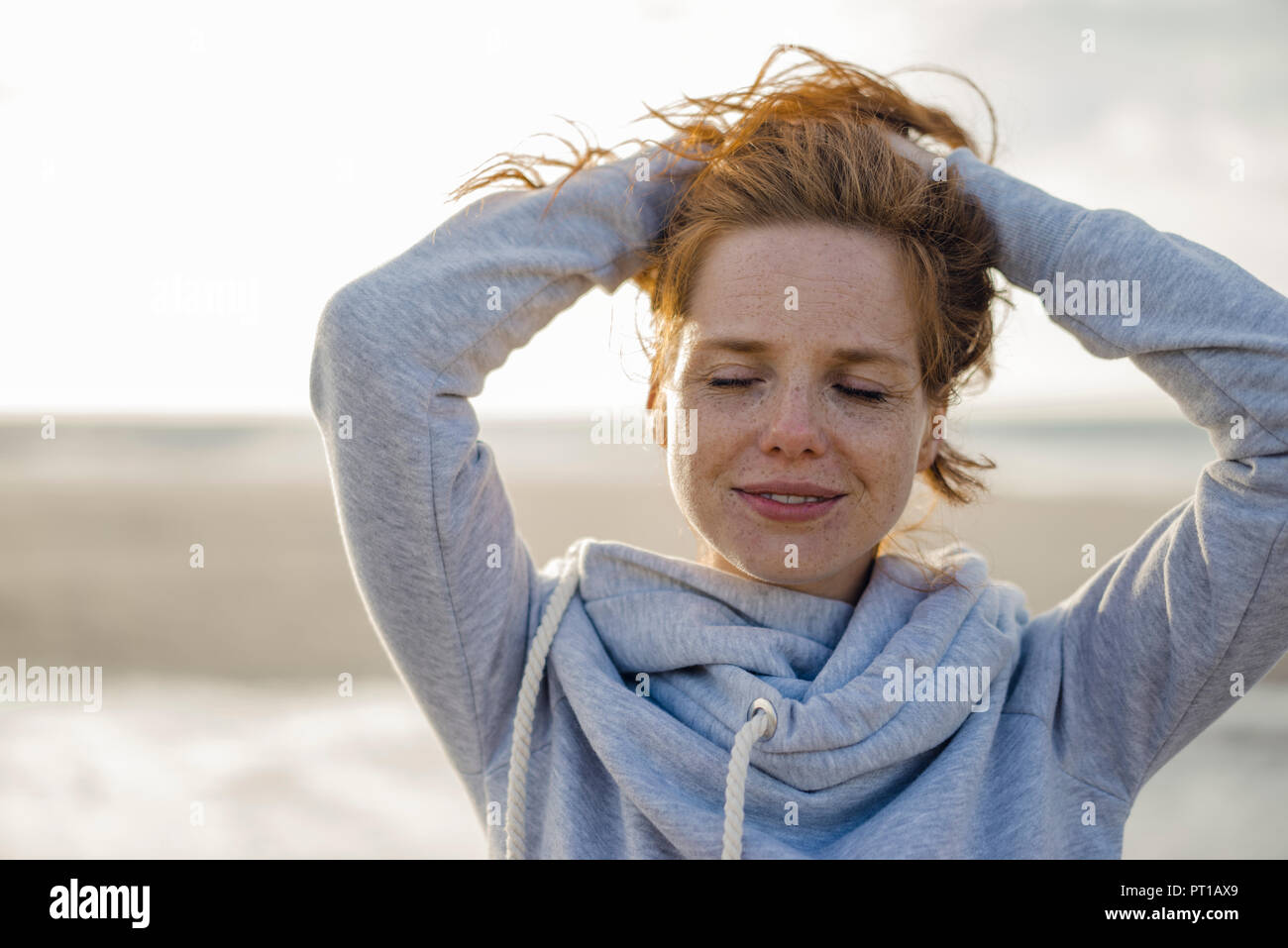 Redheaded donna godendo di aria fresca in spiaggia Foto Stock