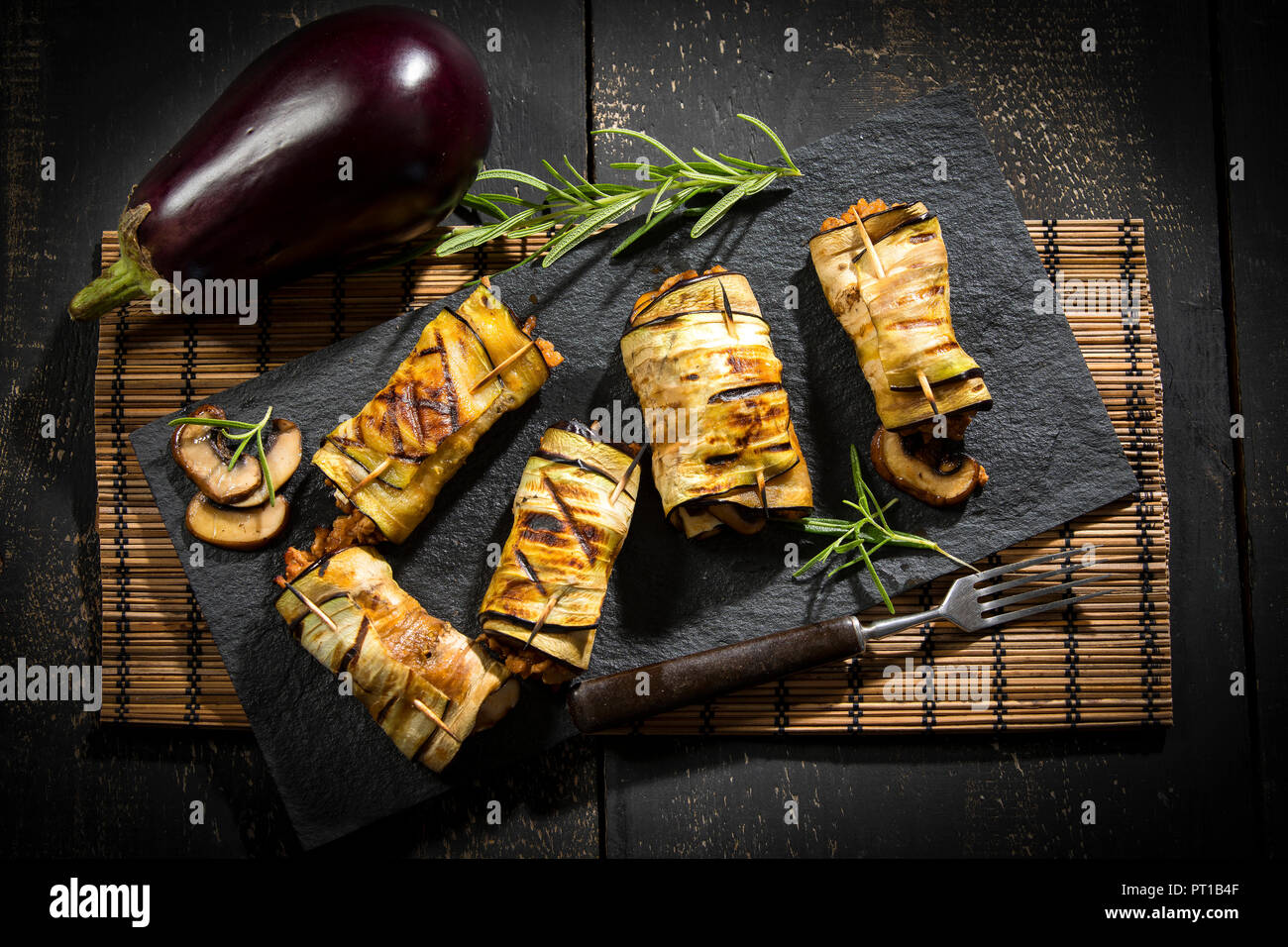 Fette di melanzane grigliate farcite con carne macinata, champignon e formaggio di capra su lavagna Foto Stock