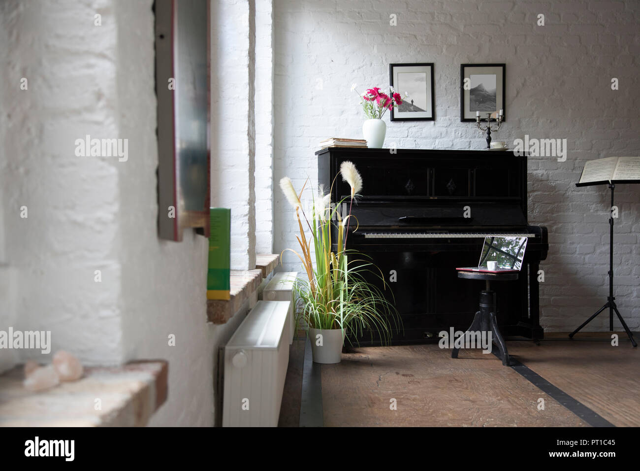 Il pianoforte con il computer portatile su uno sgabello in confortevole appartamento loft Foto Stock