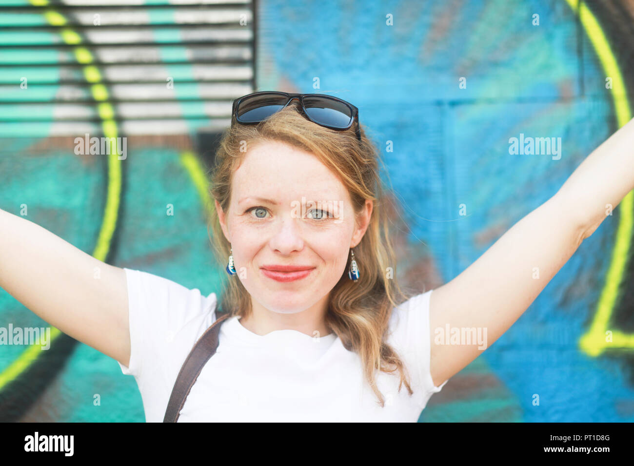 Giovane donna con braccia sollevate nella parte anteriore del graffiti Foto Stock