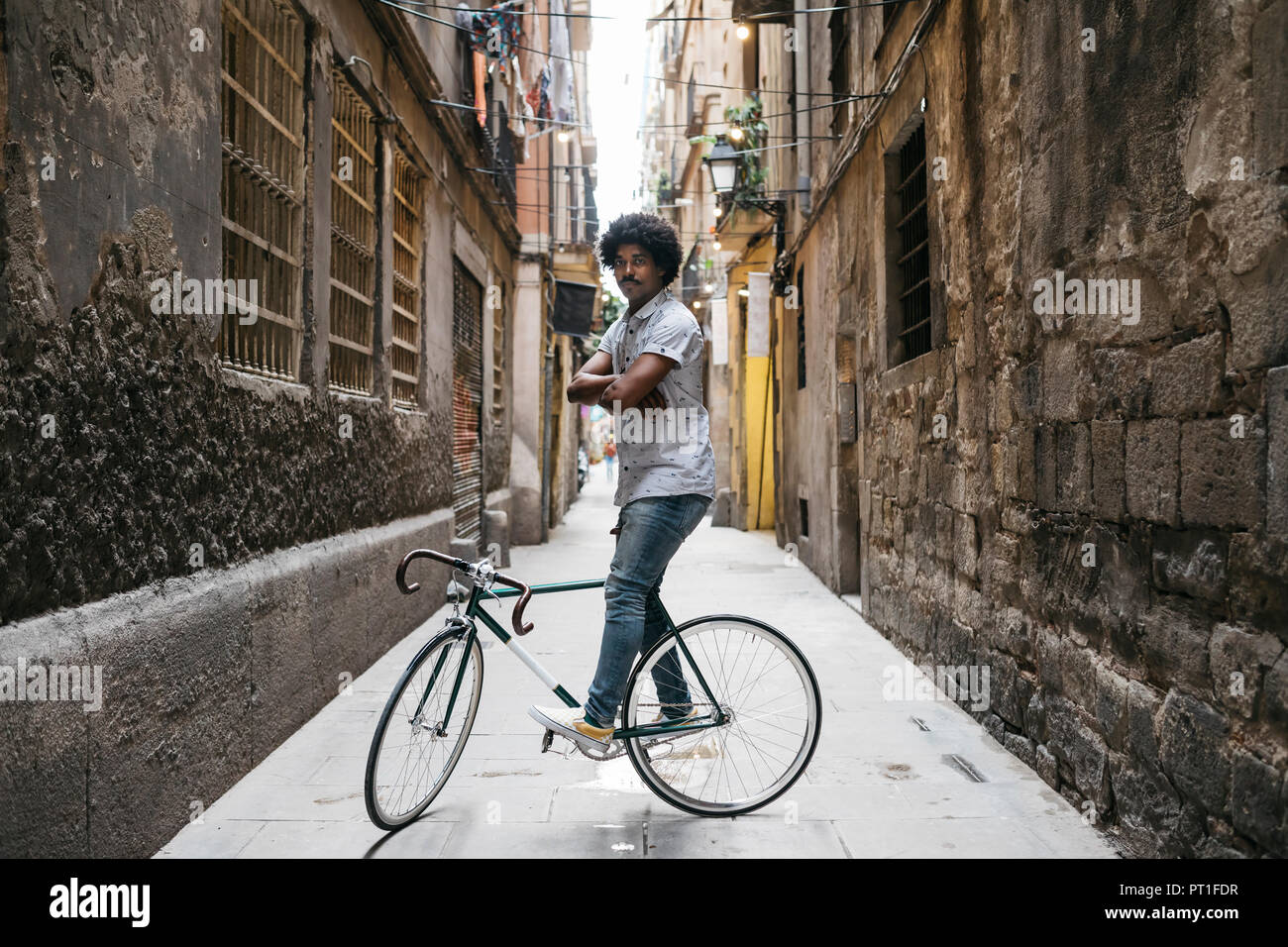 Spagna, Barcellona, man standing con ciclo di corse in un vicolo Foto Stock
