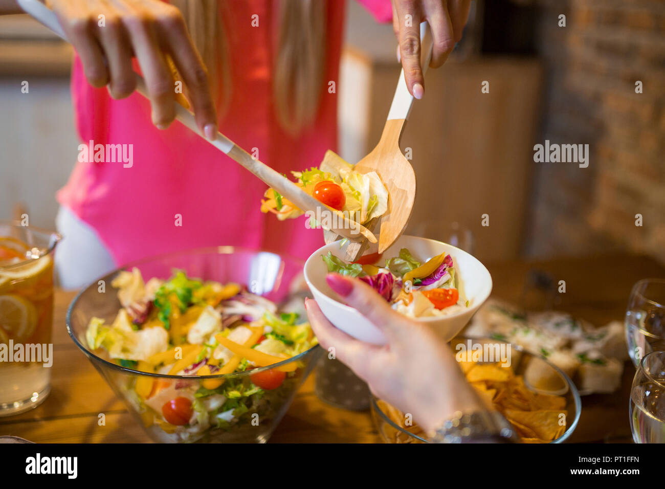 Close-up di donna incavature fino insalata per amico durante la cena a casa Foto Stock