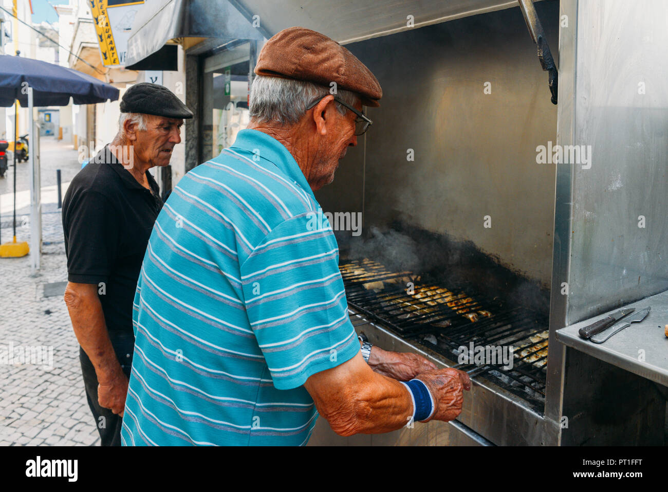 Nazare, Portogallo - 25 settembre, 2018: due uomini portoghese il barbecue di pesce fresco su un grill presso la località balneare di nazare, Portogallo Foto Stock