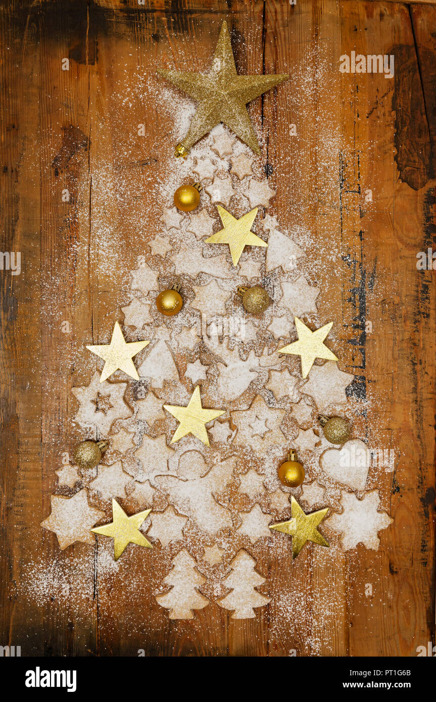 Biscotti di Natale e golden baubles di Natale e stelle formando albero di Natale su legno Foto Stock