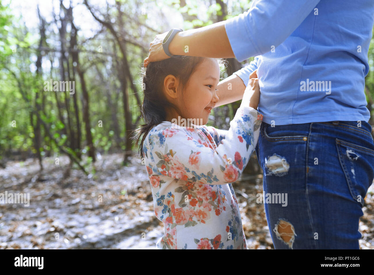 Figlia di toccare madre della pancia in un parco Foto Stock