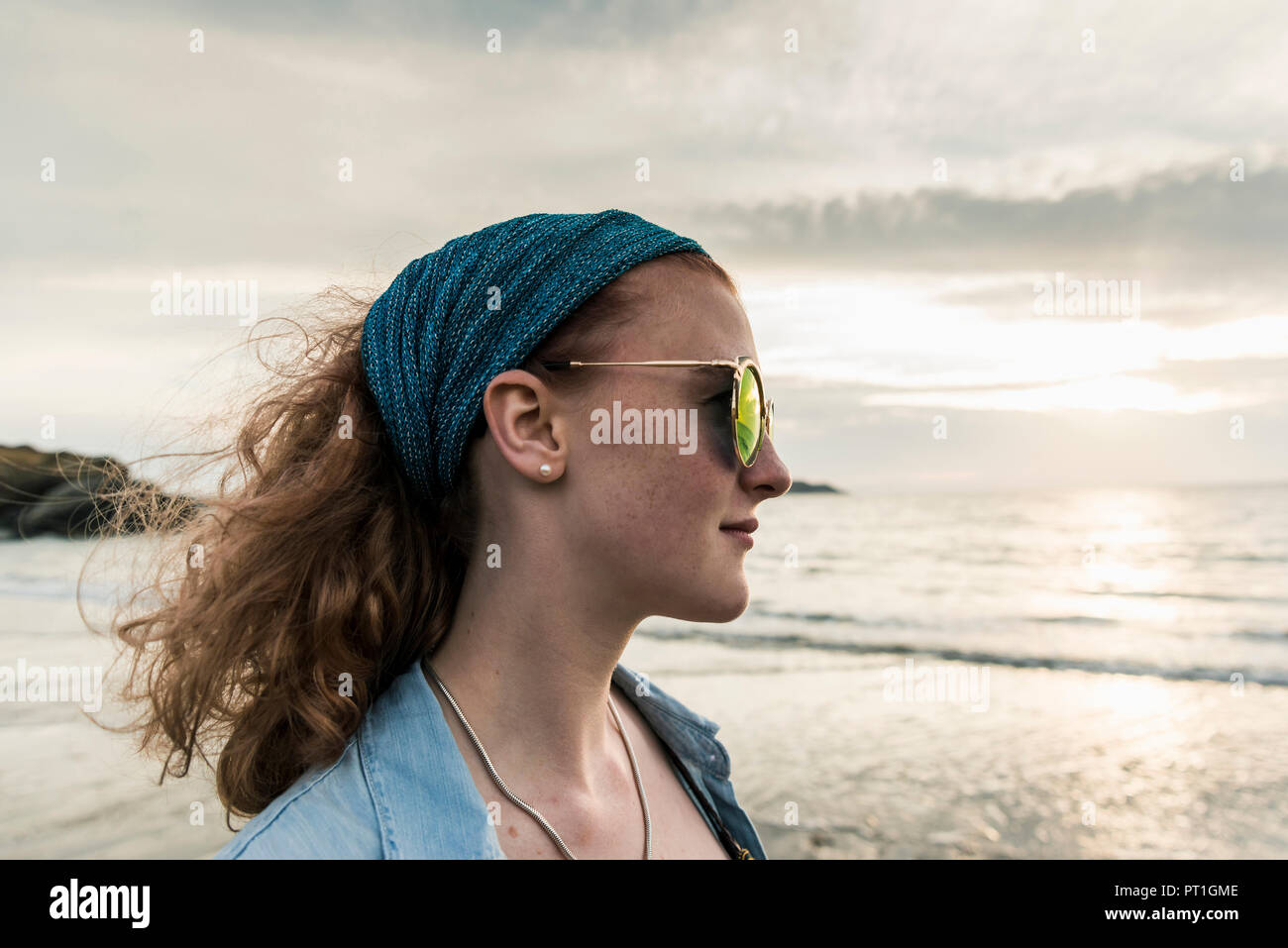 Giovane donna di guardare il tramonto sulla spiaggia Foto Stock