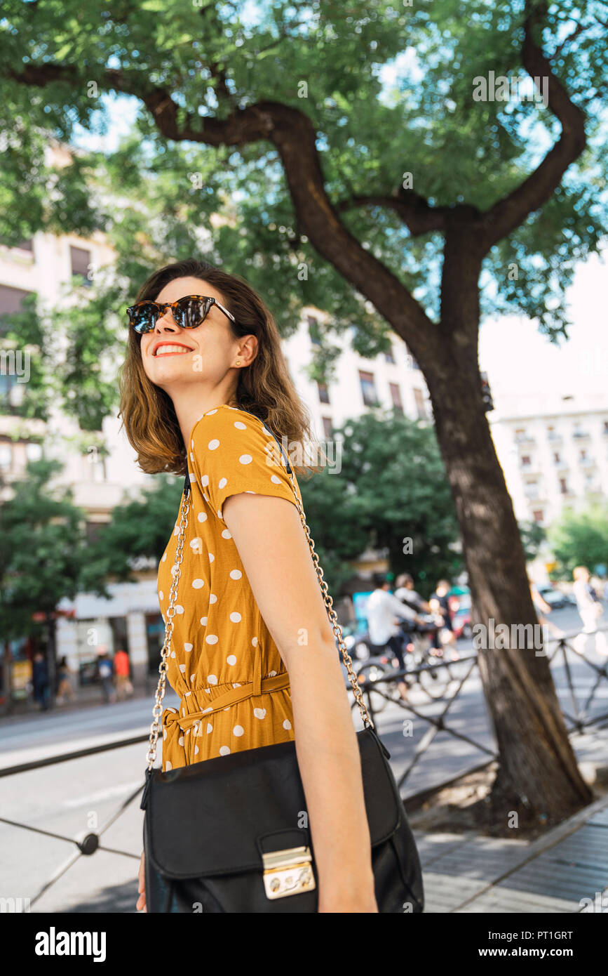 Bella donna che indossa abiti di colore giallo con la polka dots, passeggiate in città Foto Stock