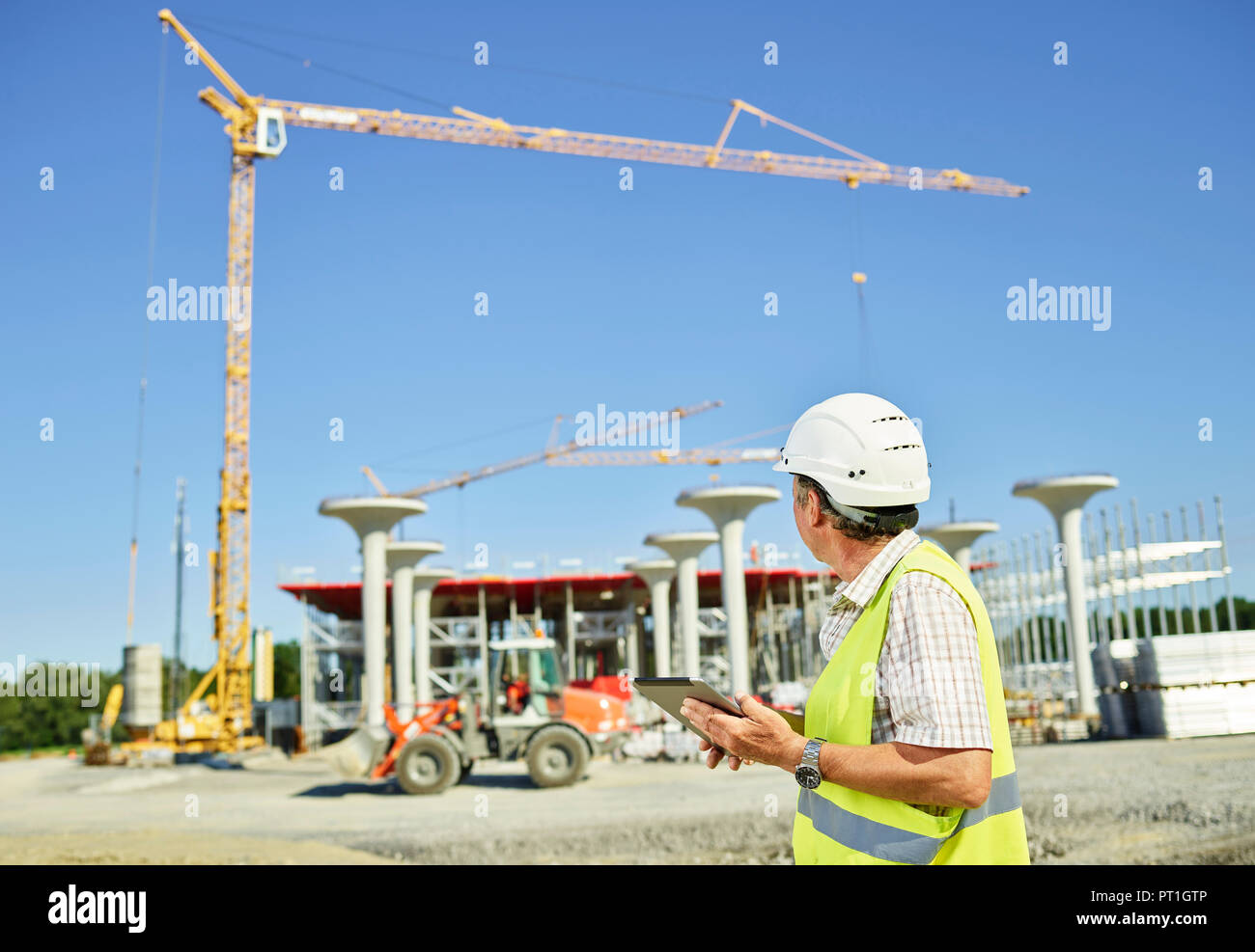Lavoratore sul sito di costruzione utilizzando tavoletta digitale Foto Stock