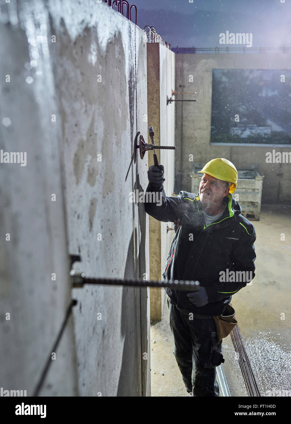 Operaio edile raccordo con un martello il tondino di ferro Foto Stock