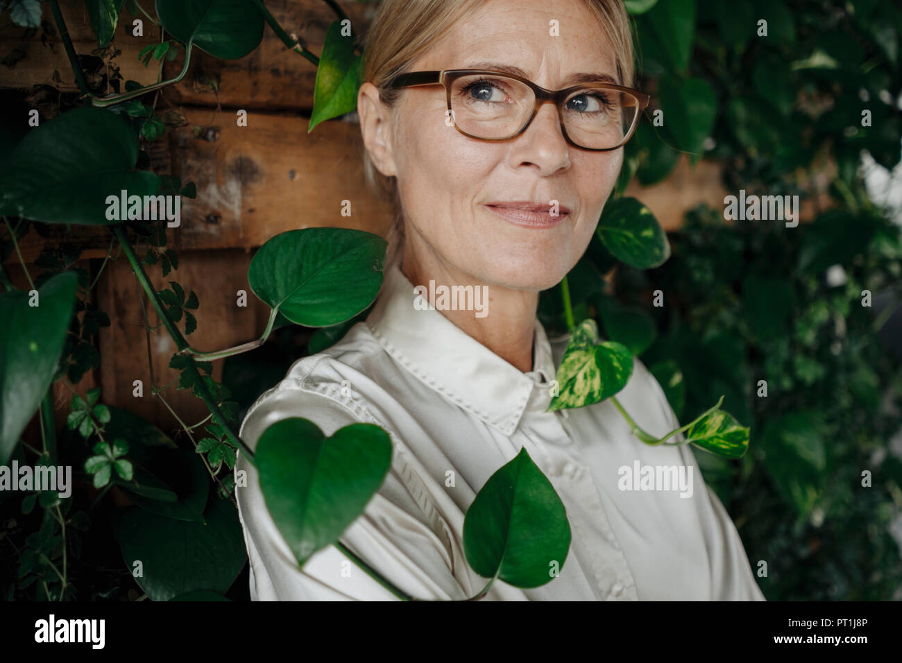 Ritratto di imprenditrice a parete con piante rampicanti Foto Stock
