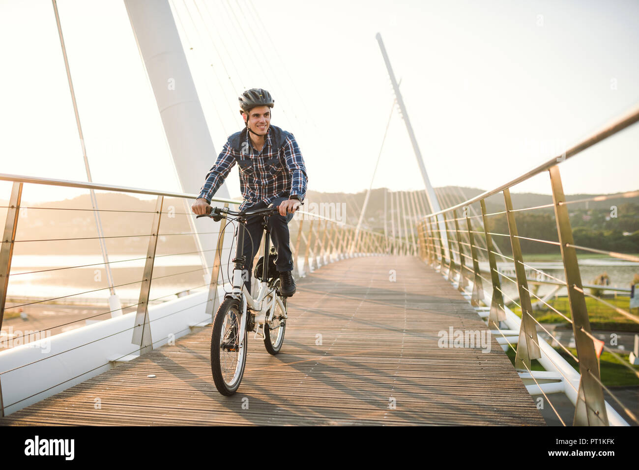 Giovane uomo Bicicletta Equitazione su un ponte al tramonto Foto Stock