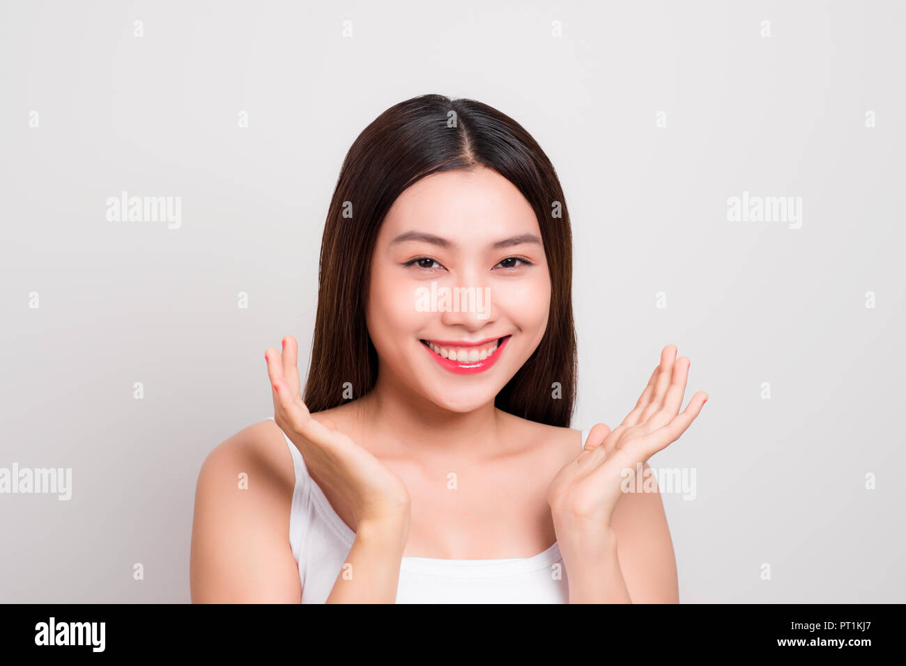 Ragazza asiatica mano guancia e sorriso attraente. Pelle il concetto di assistenza sanitaria Foto Stock