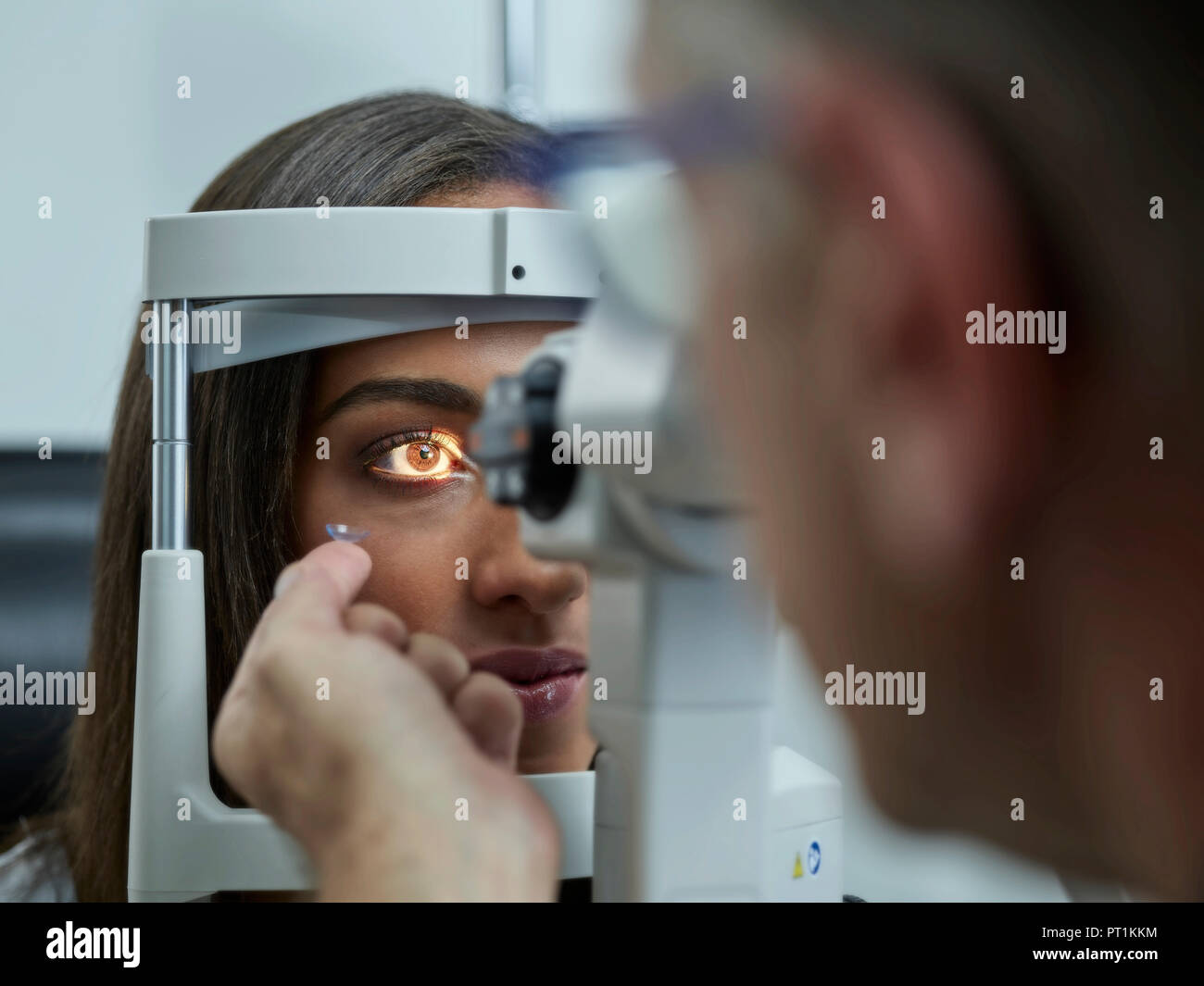 All'ottico optometrista esaminando giovane donna's eye, la lente a contatto sul dito indice Foto Stock