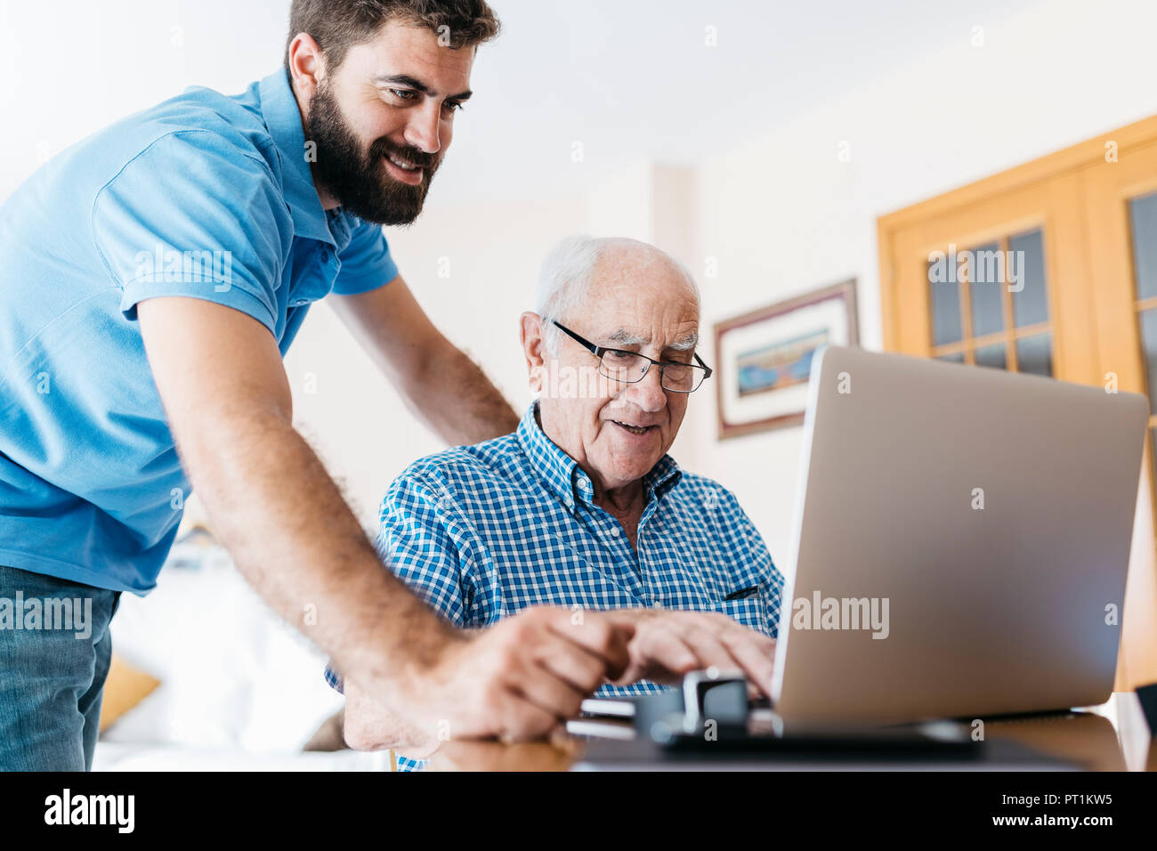 Nipote di adulti insegnamento a suo nonno per uso portatile Foto Stock