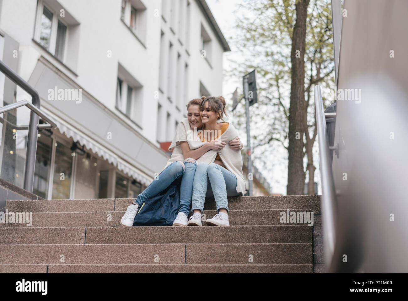 Amici seduti sulle scale nella città, cardigan di condivisione Foto Stock