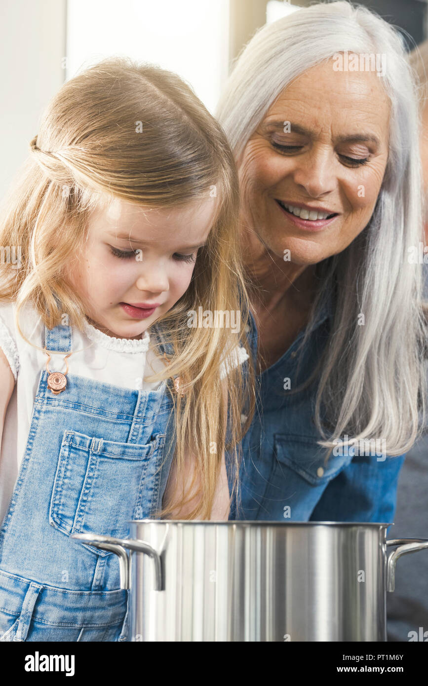 Nonna e nipote cucinare insieme, guardando pot Foto Stock