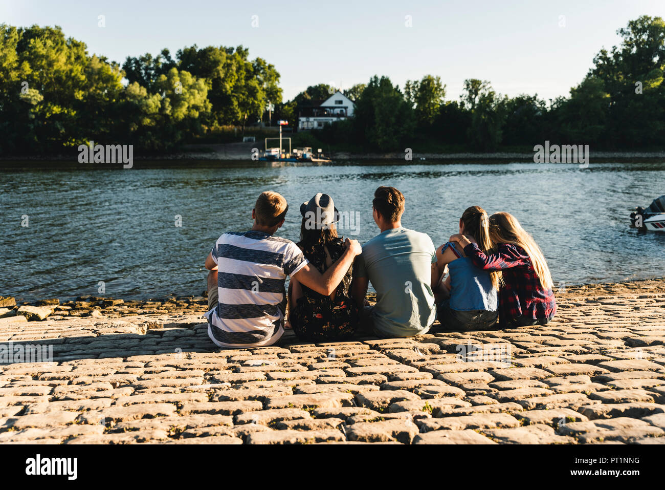 Gruppo di amici seduti a l'acqua guardando fuori Foto Stock
